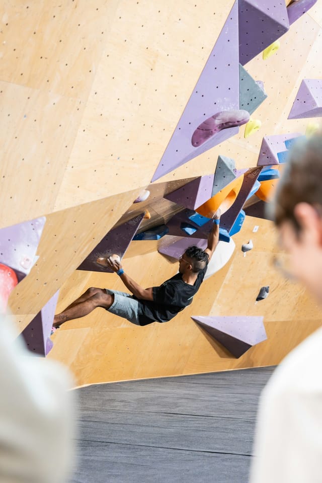 grimpeur dans une salle d'escalade qui grimpe sur un bloc entre les volumes